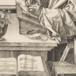 picture of book, desk and a person writing (showing from neck down)